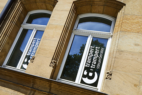 trampert & trampert steuerberater Fensterbeklebung Logo weiß, Altbau Sandsteinmauer, Aufnahme dynamisch schräg